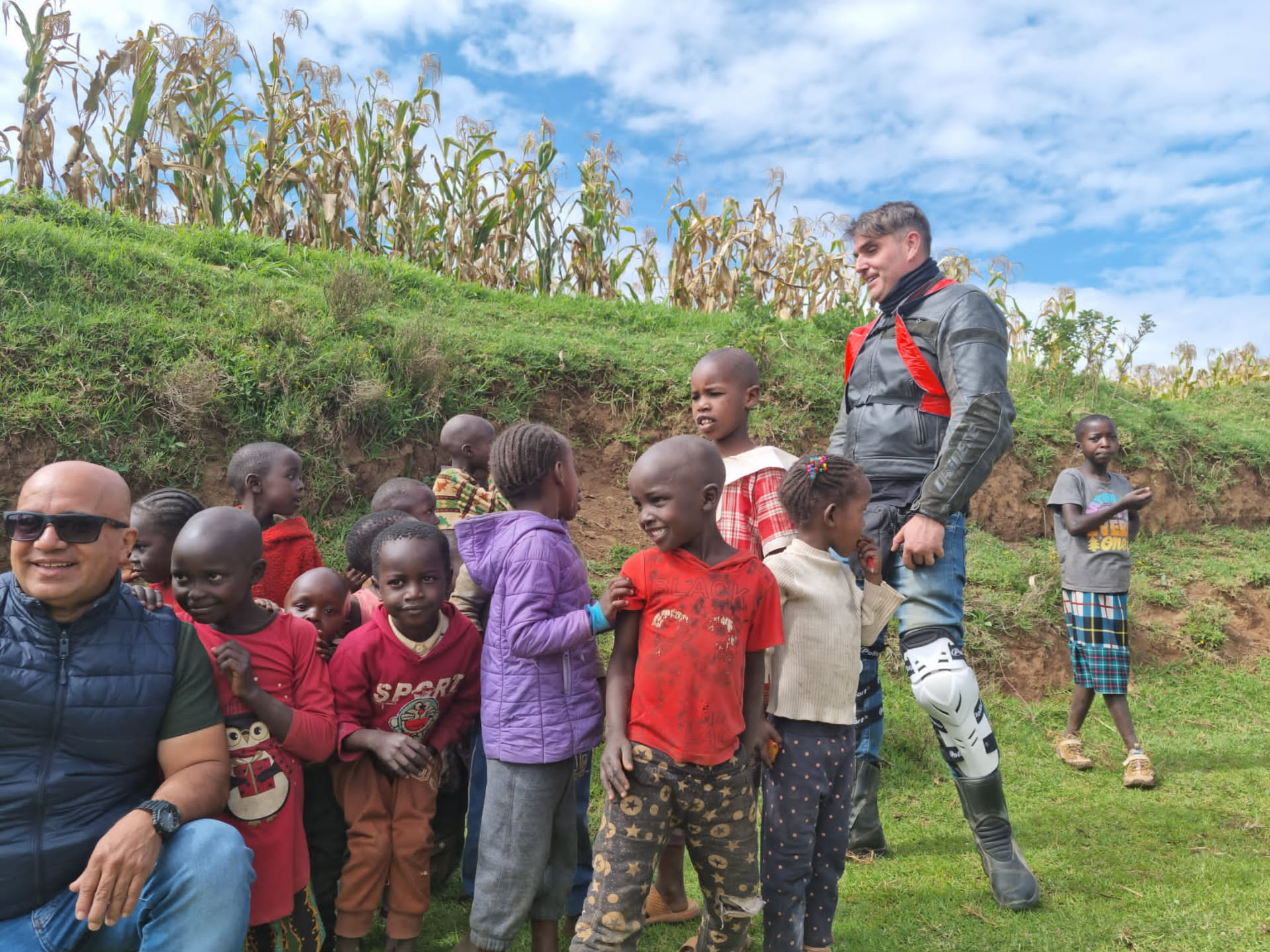 Grupo de niños saludando junto a las motos de RAFIKI en Kenya